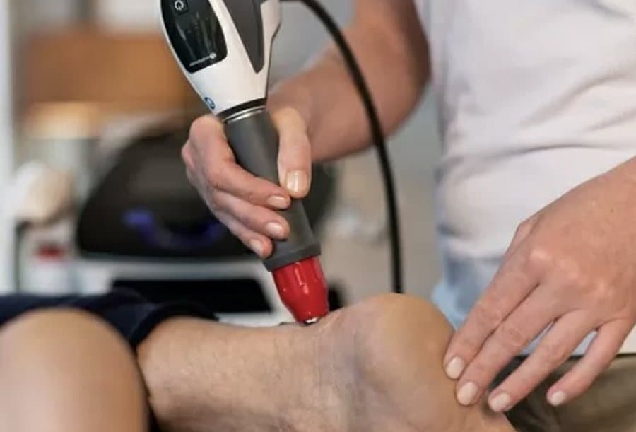 A shockwave probe being applied to a patient's knee during treatment